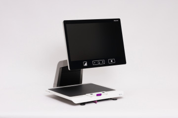 Rehan Electronics Acuity Speech desktop magnifier with a widescreen display mounted on an adjustable arm above a reading platform, shown against a white background.