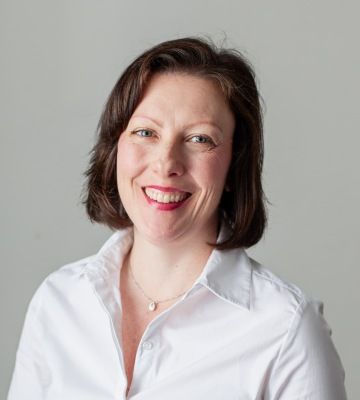 A photo of Matapo's business development manager, Lorna Straka. She has light brown hair that reaches her shoulders and blue eyes, and is smiling broadly while wearing a white collared shirt against a neutral background.