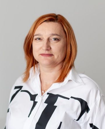 A photo of Matapo's Operations Manager, Martina Skalská. She has short light ginger hair and brown eyes. She is wearing a white collared shirt with black lettering against a neutral background.